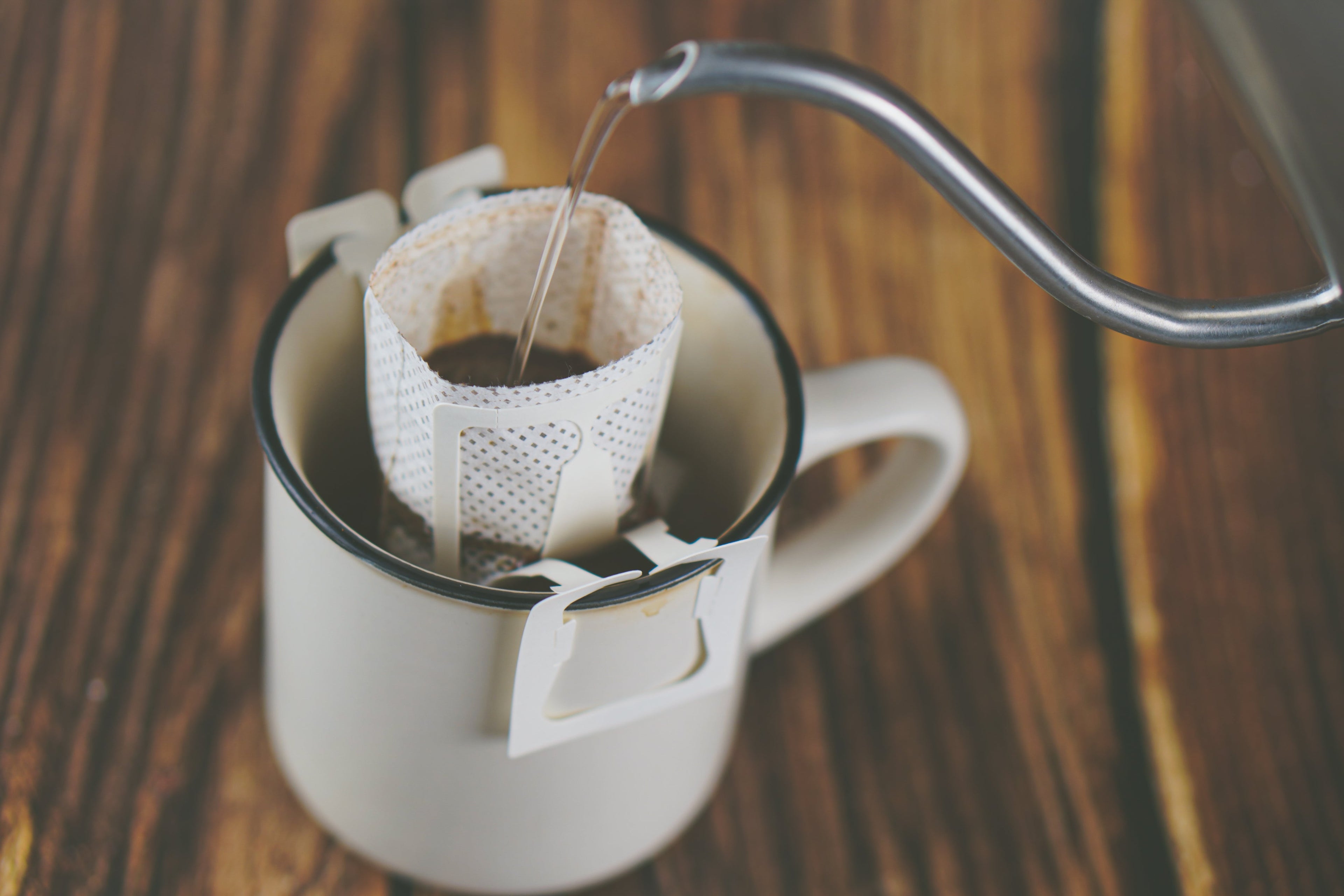 Filter being poured into a white mug on a wooden surface
